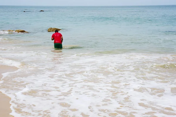 Güzel bir plaj, beyaz dalgalar, kayalar ve balıkçı tekneleri, esinti, güneş parlak gün ışığında beyaz kum plaj.