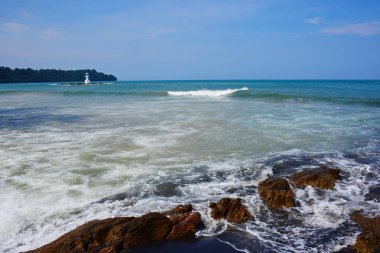 Güzel bir plaj, beyaz dalgalar, kayalar ve balıkçı tekneleri, esinti, güneş parlak gün ışığında beyaz kum plaj.