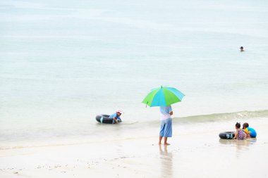 Turistler plajda yüzüyor. Ve kumlu plaj boyunca yürüyüş yapın. Şemsiye yağmurlu bir günde sahilde, Sattahip, Chonburi, Tayland tarihinde 28 Nisan 2018 kullanmanız gerekir.