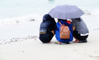 Turistler plajda yüzüyor. Ve kumlu plaj boyunca yürüyüş yapın. Şemsiye kullanmanız gerekir beach, Sattahip, Chonburi, Tayland üzerinde Nisan 28, bir yağmur fırtınası ile yağmurlu bir gün 2018.Travelers ayakkabı plajda yerleştirilir. Kum oyuncakları ve 