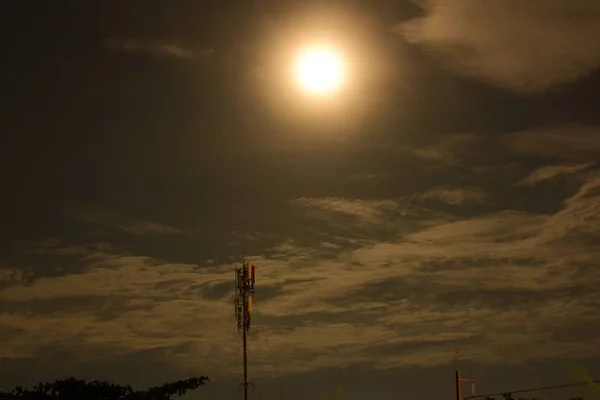 Full moon with clouds during beautiful night and tower of communication technology network