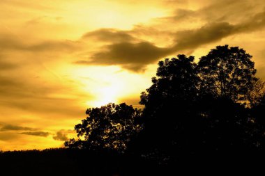 Gündoğumu veya günbatımı dağ, sabahın erken saatlerinde. Altın, güzel ve renkli gökyüzüdür. Güneş battığında, güneşin battığı. Toprak yol ve yeşil ağaçlar girişidir.
