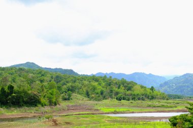 Dağlar, mavi gökyüzü ve parlak gün içinde güzel bulutlar görünümünü. akarsu yeşil ormanlar arasında. Nehir ve Khao Laem Barajı, Sangklaburi, Thailand.2018 Mayıs 5 Pzt köprüde baraja çevreleyen toplulukların görünümü.