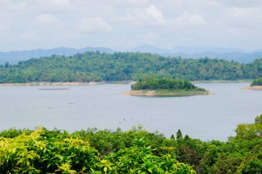 Dağlar, gökyüzü, yeşil ormanlar arasında akarsu manzarası. Mavi gökyüzü ve parlak gün içinde güzel bulutlar.