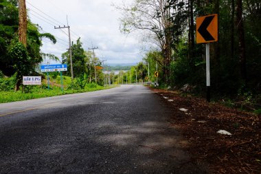 Dağ yolundan ağaçları ile. Manzaralı yoldan yeşil ağaçlar ve gökyüzü vardır. Tayland seyahat.