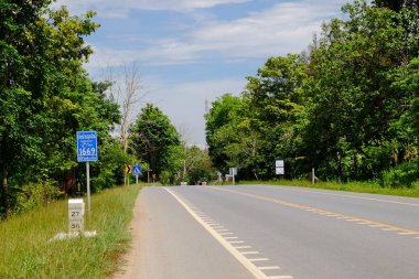 Dağ yolundan ağaçları ile. Manzaralı yoldan yeşil ağaçlar ve gökyüzü vardır. Tayland seyahat.