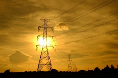 Yüksek gerilim iletim gönder elektrik santrali insanlara kuleleri. Günbatımında ile gökyüzü altın