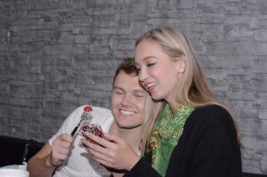 Çift bir cep telefonu kullanıyor ve restoranda yemek.