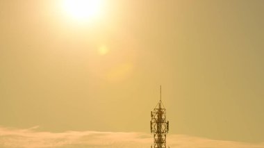 Gün batımı arka planında uzun elektrik kulesi