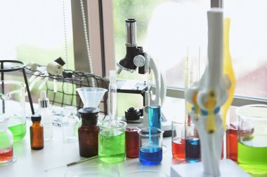 Cam test tüpleri ve mavi zemin üzerinde renkli sıvıyla moleküler yapısı olan mataralar.