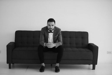 Kanepede oturan zarif adamın tek renkli fotoğrafı.