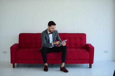 Koltukta otururken tablet bilgisayar kullanan şık bir adam. 