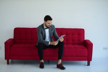 Koltukta otururken tablet bilgisayar kullanan şık bir adam. 