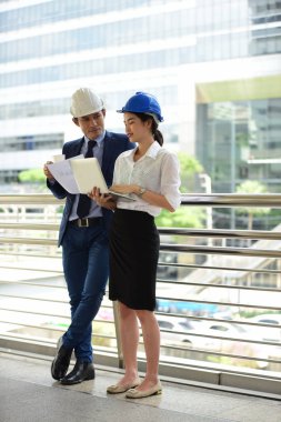 İki mimar inşaat alanında dizüstü bilgisayar kullanıyor.