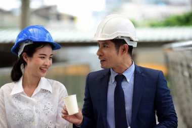 İki mimar inşaat alanında konuşuyor.