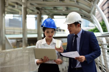 İki mimar inşaat alanında dizüstü bilgisayar kullanıyor.