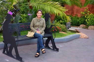 Genç kadın gündüz vakti dışarıda poz veriyor. 