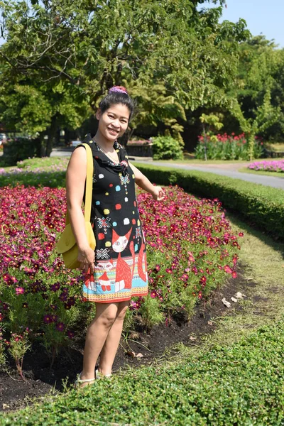 年轻的亚洲女人在花园里摆姿势 白天开着五颜六色的花 — 图库照片
