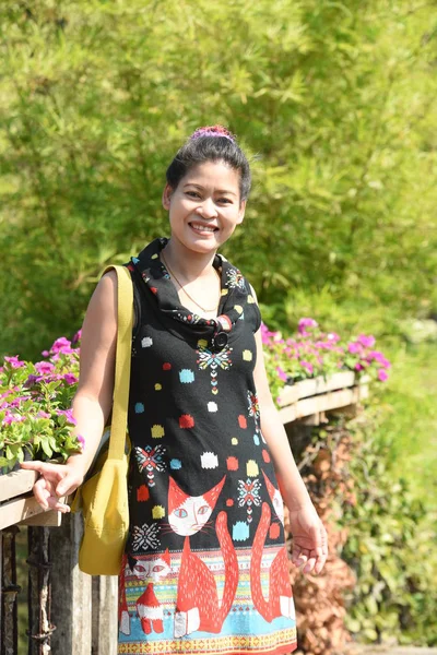 昼間は色とりどりの花で花公園にポーズをとる若いアジア人女性 — ストック写真