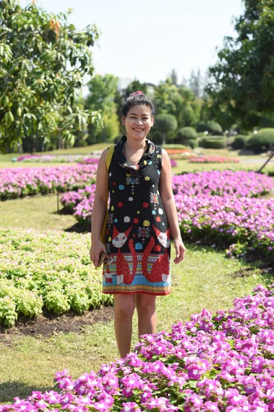 昼間は色とりどりの花で花公園にポーズをとる若いアジア人女性 — ストック写真