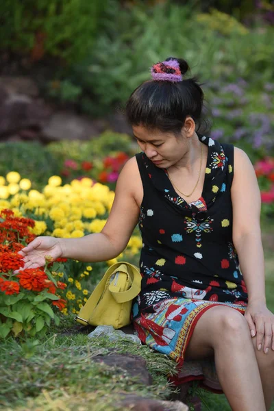 昼間は色とりどりの花で花公園にポーズをとる若いアジア人女性 — ストック写真