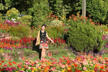 Genç Asyalı bir kadının portresi Çiçek parkında gündüz vakti renkli çiçeklerle poz veriyor  