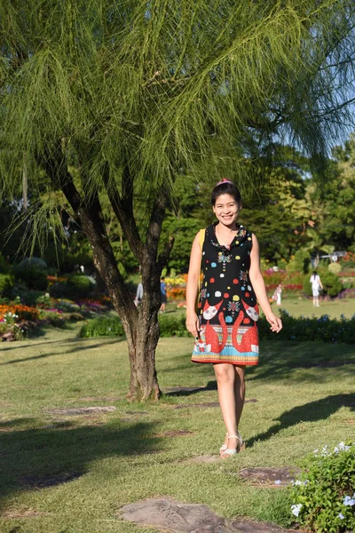 昼間は色とりどりの花を咲かせ花公園にポーズをとる若いアジア人女性の肖像 — ストック写真