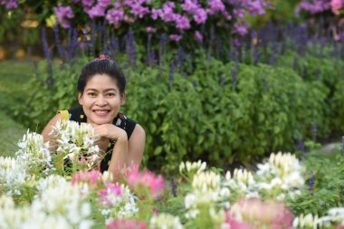 Genç Asyalı bir kadının portresi Çiçek parkında gündüz vakti renkli çiçeklerle poz veriyor  