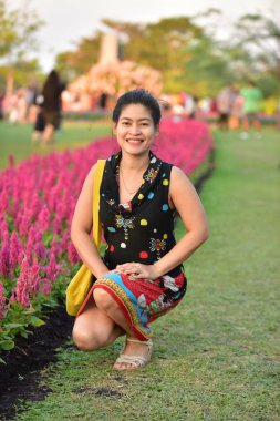 Genç Asyalı bir kadının portresi Çiçek parkında gündüz vakti renkli çiçeklerle poz veriyor  