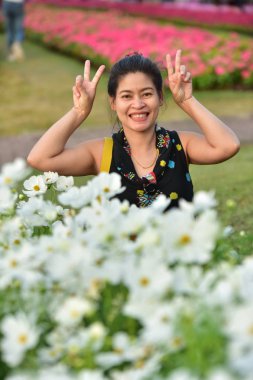 Genç Asyalı bir kadının portresi Çiçek parkında gündüz vakti renkli çiçeklerle poz veriyor  