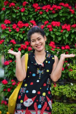 Genç Asyalı bir kadının portresi Çiçek parkında gündüz vakti renkli çiçeklerle poz veriyor  