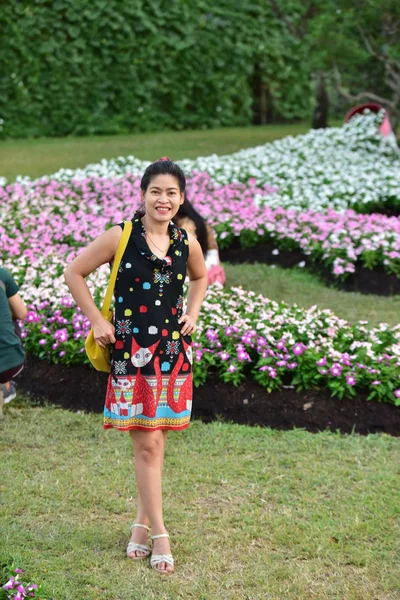 昼間は色とりどりの花を咲かせ花公園にポーズをとる若いアジア人女性の肖像 — ストック写真