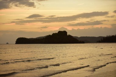 Kumsaldaki turist silueti ve gün batımından sonraki ışık.
