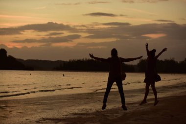 Kumsaldaki turist silueti ve gün batımından sonraki ışık.