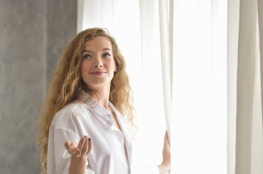 Evdeki pencerenin yanında güzel genç bir kadın.