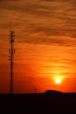 Güneşin batışı, şehir merkezindeki iş alanı günbatımı gökyüzü, kablosuz telefon direği ve sabahın erken saatlerinde turuncu-sarı gökyüzü.