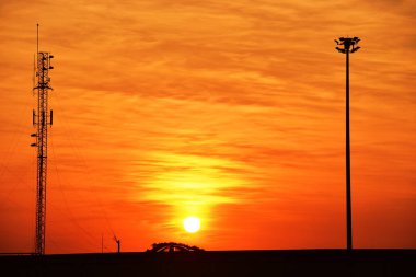 Güneşin batışı, şehir merkezindeki iş alanı günbatımı gökyüzü, kablosuz telefon direği ve sabahın erken saatlerinde turuncu-sarı gökyüzü.