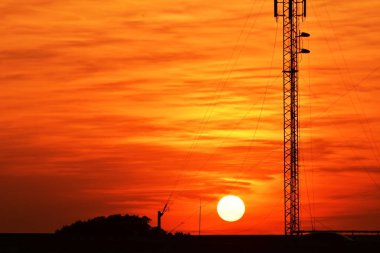 Güneşin batışı, şehir merkezindeki iş alanı günbatımı gökyüzü, kablosuz telefon direği ve sabahın erken saatlerinde turuncu-sarı gökyüzü.