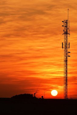 Güneşin batışı, şehir merkezindeki iş alanı günbatımı gökyüzü, kablosuz telefon direği ve sabahın erken saatlerinde turuncu-sarı gökyüzü.