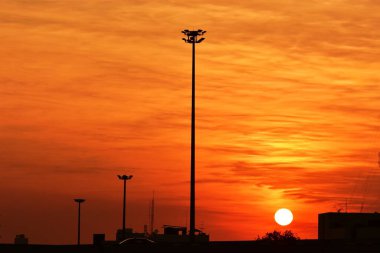 Güneşin batışı, şehir merkezindeki iş alanı günbatımı gökyüzü, kablosuz telefon direği ve sabahın erken saatlerinde turuncu-sarı gökyüzü.
