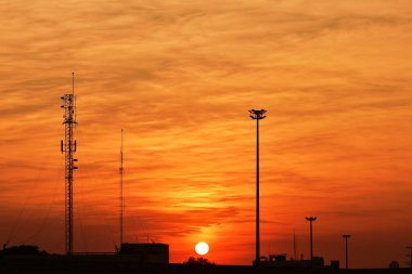 Güneşin batışı, şehir merkezindeki iş alanı günbatımı gökyüzü, kablosuz telefon direği ve sabahın erken saatlerinde turuncu-sarı gökyüzü.