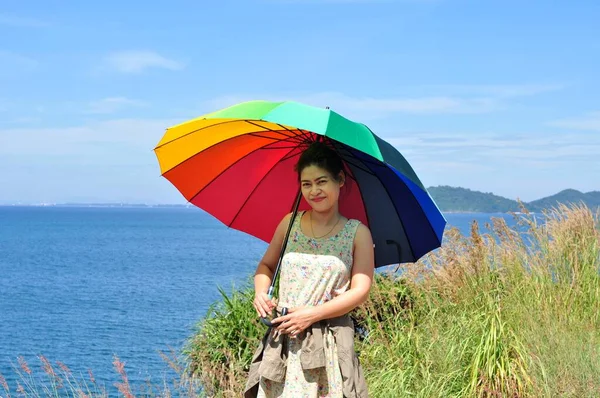 Asian woman with umbrella on sea coast