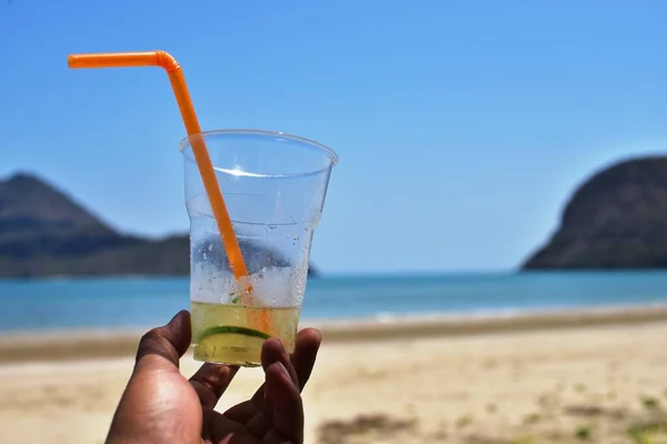 Persona Sosteniendo Vidrio Con Jugo Playa Del Mar —  Fotos de Stock