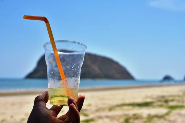 Persona Sosteniendo Vidrio Con Jugo Playa Del Mar —  Fotos de Stock