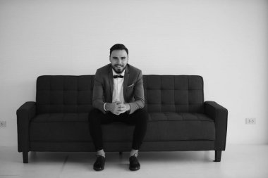 Tablet bilgisayarla koltukta oturan takım elbiseli iş adamı.