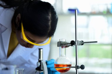 Bilimadamları bilim laboratuarlarında çalışıyor. Kovid19 için mikroskop araştırması yapan genç bir bilim adamı ve bilim adamının yakın çekimi..