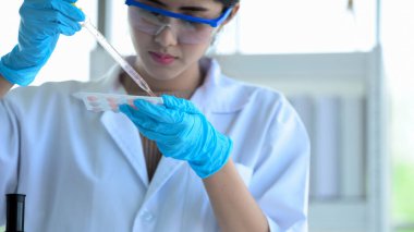 Genç kadın bilim adamları labradorda bilim deneyleri yapıyorlar. Laboratuvarda deney tüpü tutan bilim adamı, bir bilim adamının, bir mikroskopta araştırma yapan genç bir bilim adamının yakın plan fotoğrafı. Kovid19 için ilaç..