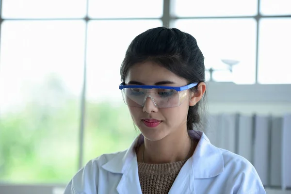 Young women scientists are experimenting with science at the lab.Asian scientist holding a test tube in a laboratory,Close-up of a scientist,Young scientist looking through a microscope in a laboratory doing research,medicine for kovid19.