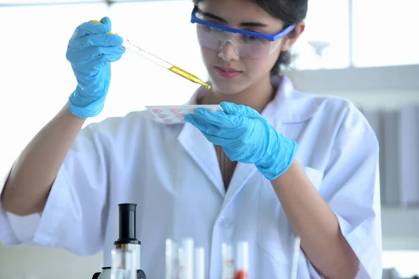 Young women scientists are experimenting with science at the lab.Asian scientist holding a test tube in a laboratory,Close-up of a scientist,Young scientist looking through a microscope in a laboratory doing research,medicine for kovid19.