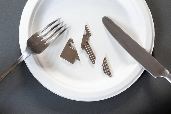 Koyu gri arka planda beyaz bir plaka, üzerinde bir çatal ve bir masa bıçağı bulunan üç parçaya ayrılmış metal bir anahtar bulunur. Diyet bulimia anarexia.